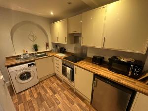 a kitchen with white cabinets and a wooden floor at Petteril House - Ground Floor in Carlisle