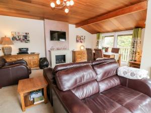 a living room with a leather couch and a table at Lodge 27 in Bideford