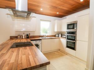 a kitchen with white cabinets and a wooden counter top at Lodge 27 in Bideford