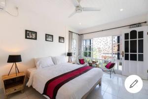a white bedroom with a large bed and a window at Beach House Apartment in Legian