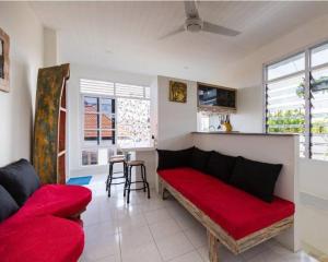 a living room with a red couch and a kitchen at Beach House Apartment in Legian