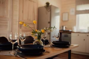 una mesa con platos y vasos y un jarrón con flores en Domki Kacprowy w Lipnicy en Lipnica