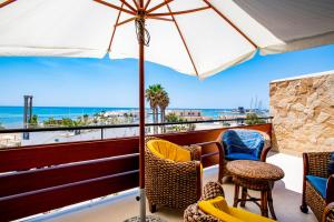 einen Balkon mit Stühlen, einem Sonnenschirm und dem Meer in der Unterkunft DELPOSTO Marina di Ragusa (elt) in Marina di Ragusa