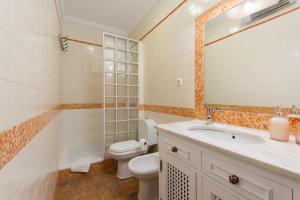 a bathroom with a toilet and a sink and a mirror at Casa das Tulipas - Vila Nogueira de Azeitão in Villa Nogueira