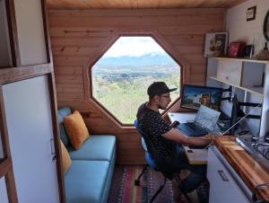 a man sitting at a desk in a tiny house with a window at Mini Casa Barichara in Barichara