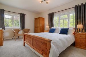 a bedroom with a large bed and two windows at Leworthy Farmhouse Bed and Breakfast in Holsworthy
