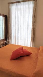 ein rotes Kissen auf einem Bett mit Fenster in der Unterkunft Appartamento Graziella, nel cuore di Ischia Porto in Ischia