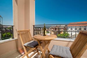 einen Tisch mit 2 Stühlen und eine Flasche Wein auf dem Balkon in der Unterkunft Luxury Apartments Ivanovic in Tivat