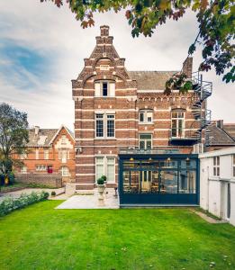 een groot bakstenen gebouw met een groen gazon bij Boutique Hotel Huys van Steyns in Tongeren