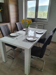 una mesa de comedor blanca con sillas y flores. en Apartma Maja, Mateja, en Koper