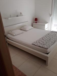 Cama en habitación blanca con cama blanca en S&M Apartments, en Drače