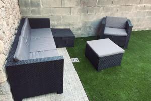 two wicker chairs and a bench on the grass at Cal Patola Xic in Bagá