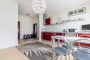 a kitchen with red cabinets and a table and chairs at Old Town Hearh Light and Open Modern Flat VIP in Klaipėda