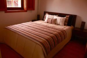 a bedroom with a large bed with a striped blanket at Casas do Fantal in Vale de Salgueiro