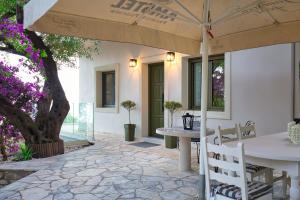 a patio with a table and chairs and an umbrella at Villa Magdalena in Barbati