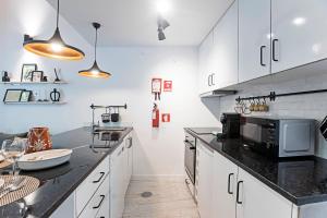 a kitchen with white cabinets and black counter tops at Vila Terra Luxury Apartments I in Vila Nova de Gaia