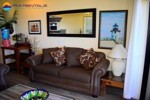 a living room with a brown couch and a mirror at Marina Pinacate A-510 in Puerto Peñasco