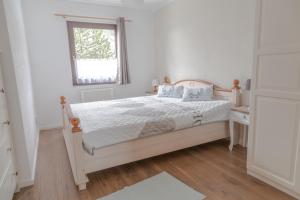 a white bedroom with a bed and a window at Kellerwald in Frankenau