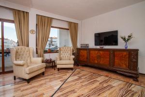 a living room with two chairs and a flat screen tv at Cesurlar Hotel in Çeşme