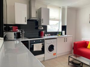 a kitchen with a washing machine and a red chair at Modern 2 Bedroom Flat in Robert st Swansea in Swansea