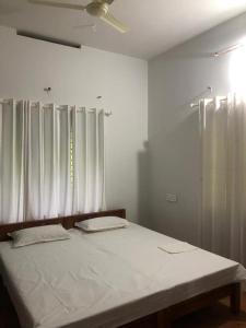 Nilambūr的住宿－H Villa，一间卧室配有一张带白色床单的床和一扇窗户。