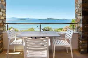 un tavolo e sedie su un balcone con vista sull'oceano di PANORAMA ROOM APARTMENs a Ouranoupoli