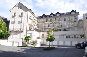 een groot wit appartementencomplex met een parkeerplaats bij Résidence Poste & Golf, appartement pour 4 personnes au cœur de Luchon in Luchon