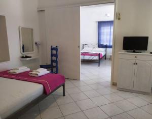a room with two beds and a tv in it at Το σπίτι της Μαργαρίτας στην παραλία in Nea Stira