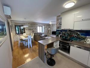 eine Küche und ein Wohnzimmer mit weißen Schränken und einem Tisch in der Unterkunft Apartment Old Town Ivo in Makarska