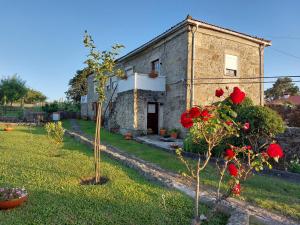 Uma casa de pedra com rosas vermelhas à frente. em Quinta da Ponte em Viana do Castelo