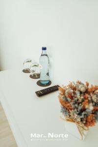 a table with a bottle and two glasses and a plant at Beach Residence Mar do Norte in Ribamar