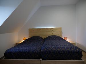 a bed with a blue comforter in a room at Le grenier des hirondelles Gîte appartement au coeur de la route des vins d'Alsace in Rouffach