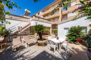 patio ze stołem i krzesłami przed budynkiem w obiekcie Villa Amorós w Cala Ratjada
