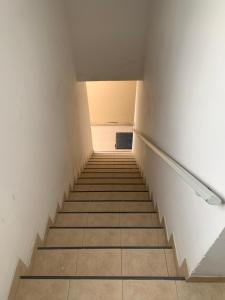 a staircase in an empty room with white walls and tile floors at Dpto Lyon in General Roca