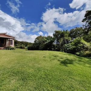 a large grassy yard with a house and trees at Monteverde House in Monteverde Costa Rica