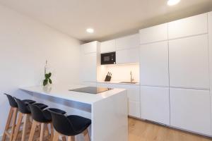 a kitchen with white cabinets and a island with stools at Itan home in Gran Tarajal