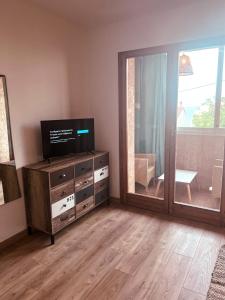 uma sala de estar com televisão numa cómoda e uma porta de vidro deslizante em Studio Roncu em Calvi
