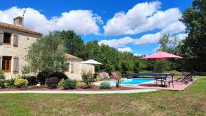 - une piscine avec une table, des chaises et un parasol dans l'établissement Au Clos Des Templiers, à Puyravault