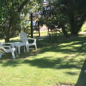 dos sillas blancas y una mesa en el césped en Solar Pampa Apart en Mar de las Pampas