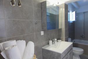 ein Badezimmer mit einem Waschbecken, einem WC und einem Spiegel in der Unterkunft Evgenia Seafront House in Skiathos-Stadt