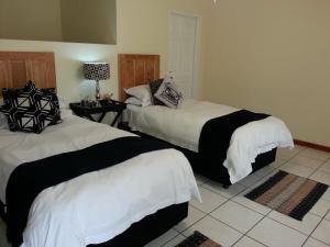 a bedroom with two beds and a table with a lamp at The Guest House Pongola in Pongola