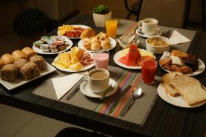 a table topped with plates of breakfast foods and drinks at Rede Andrade Vivaldi in Foz do Iguaçu