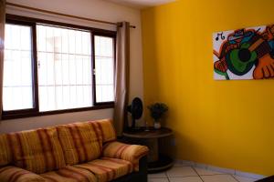 a living room with a couch and a yellow wall at EXCLUSIVE - AMPLO, FAMILIAR E PRÓXIMO DE TUDO in Cabo Frio