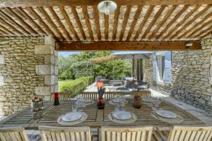 een houten tafel met stoelen en een parasol op een patio bij Villa Vermentine in Gordes