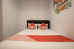 uma cama com duas almofadas e um cobertor vermelho em OYO 176 Near Cideng Virgo Residence em Jakarta