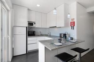 una cucina con mobili bianchi e un piano di lavoro di Sunshine Apartment ad Armação de Pêra