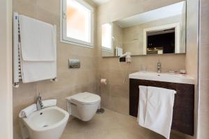 bagno con servizi igienici, lavandino e specchio di Hotel Smeraldo a Lignano Sabbiadoro