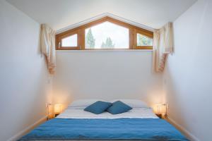 a bed with blue pillows in a room with a window at Miataland in Collazzone