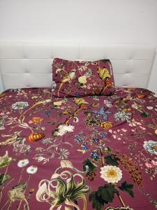 ein Bett mit einer lila Tagesdecke mit Blumen darauf in der Unterkunft Apartma D in Ližnjan