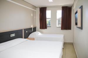 a hotel room with two beds and a window at Rede Andrade Vivaldi in Foz do Iguaçu
